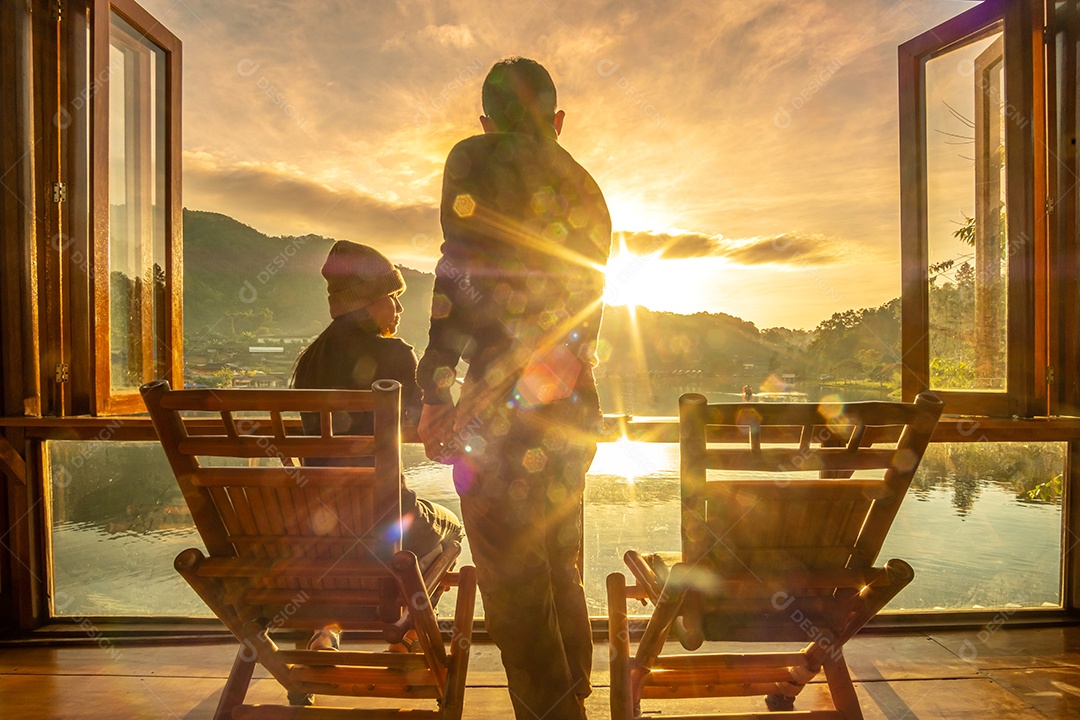 Casal jovem feliz assistindo a vista para o lago no café ao nascer do sol da manhã, vila de Ban Rak Thai, província de Mae Hong Son, Tailândia. Viagens, juntos e conceito romântico