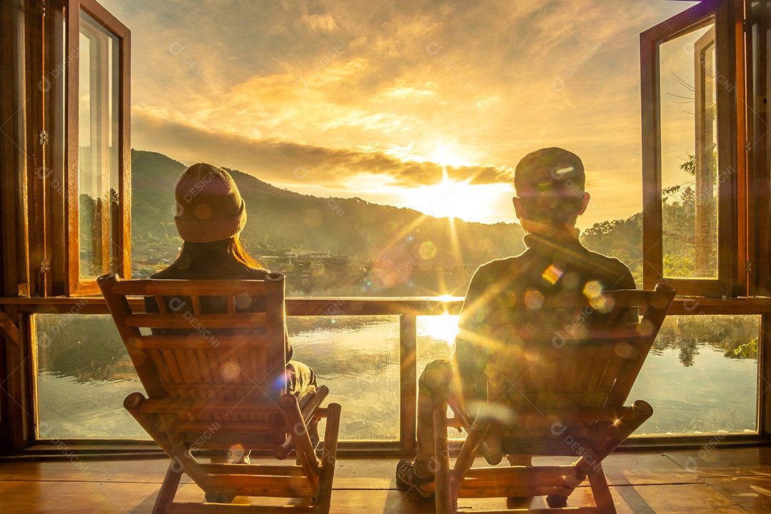 Casal jovem feliz assistindo a vista para o lago no café ao nascer do sol da manhã, vila de Ban Rak Thai, província de Mae Hong Son, Tailândia. Viagens, juntos e conceito romântico