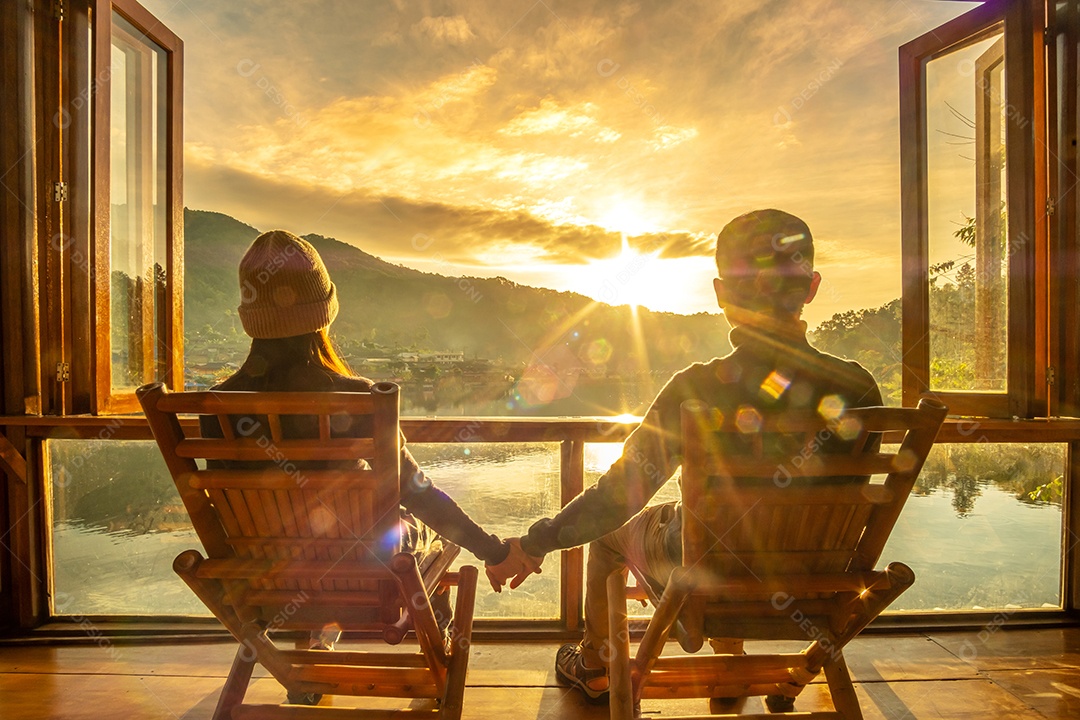 Casal jovem feliz assistindo a vista para o lago no café ao nascer do sol da manhã, vila de Ban Rak Thai, província de Mae Hong Son, Tailândia. Viagens, juntos e conceito romântico