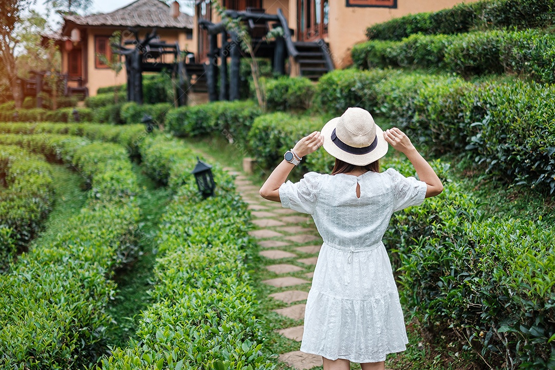 Mulher turista feliz em vestido branco desfrutar de belo jardim de flores. viagens, natureza, férias e conceito de férias