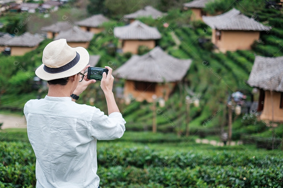 Homem de turista feliz na camisa branca tirando foto pelo smartphone móvel no belo jardim de chá. Viajante visitando a vila tailandesa de Ban Rak, Mae Hong Son, Tailândia. conceito de viagens, férias e férias
