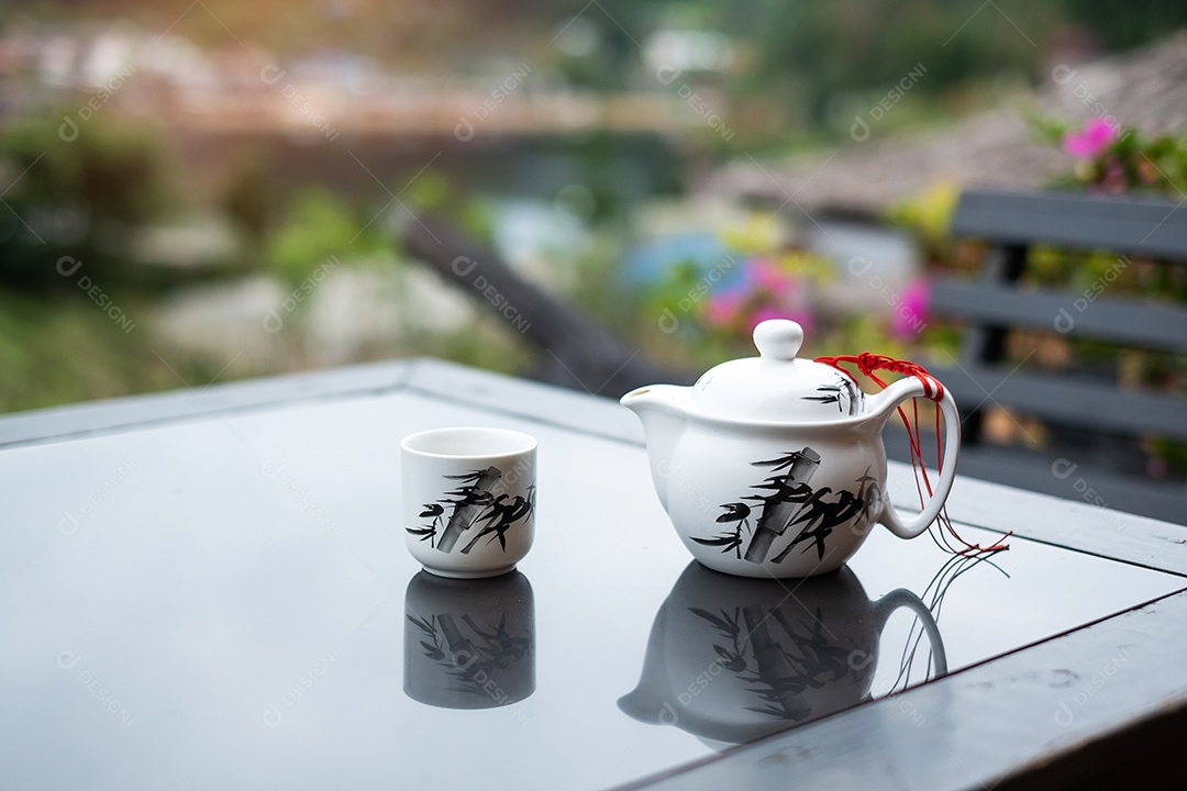 bule e chá quente para xícara na mesa de madeira contra o fundo da vista do jardim de chá pela manhã, vila de Ban Rak Thai, província de Mae Hong Son, Tailândia