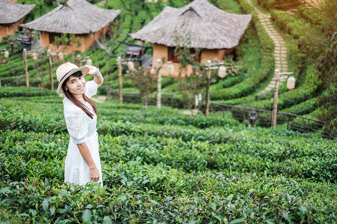 Mulher turista feliz em vestido branco desfrutar de belo jardim de chá. Viajante visitando na aldeia de Ban Rak Thai, Mae Hong Son, Tailândia. conceito de viagens