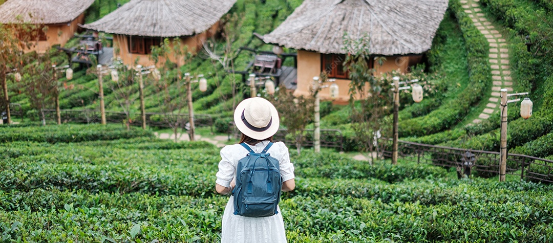 Mulher turista feliz em vestido branco desfrutar de belo jardim de chá. Viajante visitando na aldeia de Ban Rak Thai, Mae Hong Son, Tailândia. conceito de viagens