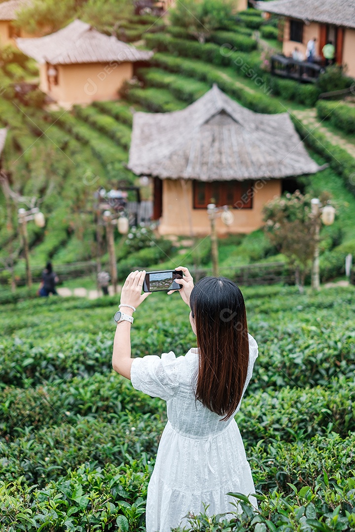 Mulher turista feliz em vestido branco desfrutar de belo jardim de chá. Viajante visitando na aldeia de Ban Rak Thai, Mae Hong Son, Tailândia. conceito de viagens
