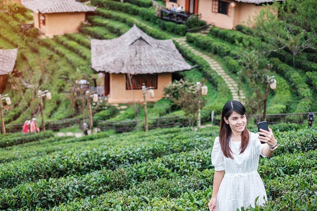 Mulher turista feliz em vestido branco desfrutar de belo jardim de chá. Viajante visitando na aldeia de Ban Rak Thai, Mae Hong Son, Tailândia. conceito de viagens