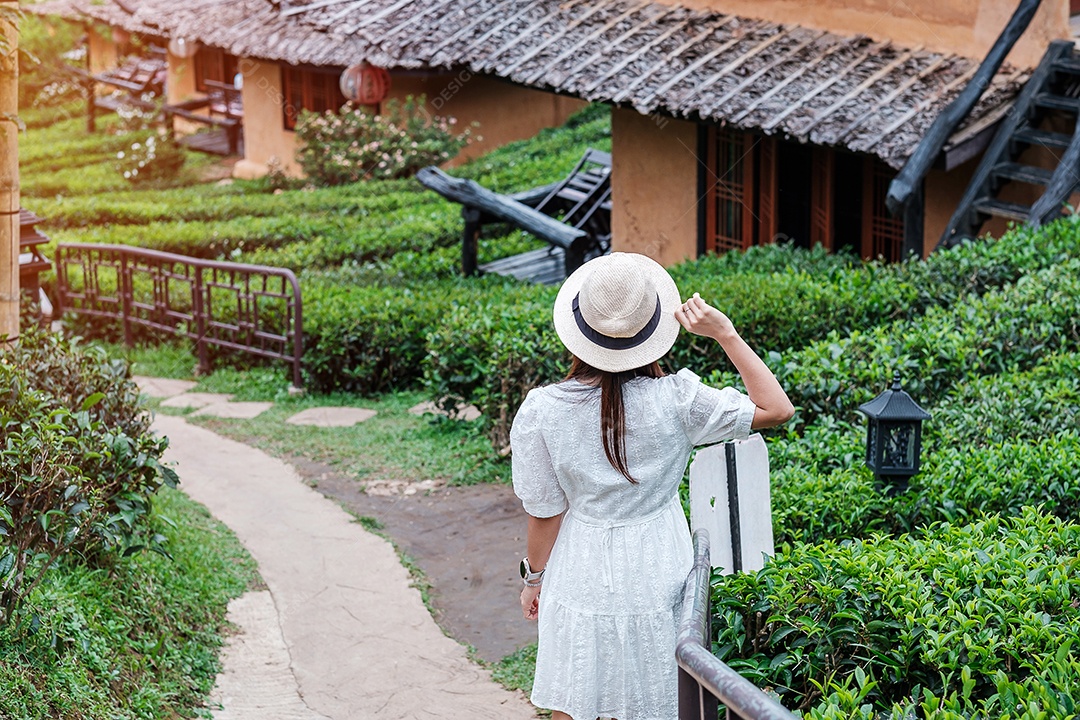 Mulher turista feliz em vestido branco desfrutar de belo jardim de chá. Viajante visitando na aldeia de Ban Rak Thai, Mae Hong Son, Tailândia. conceito de viagens