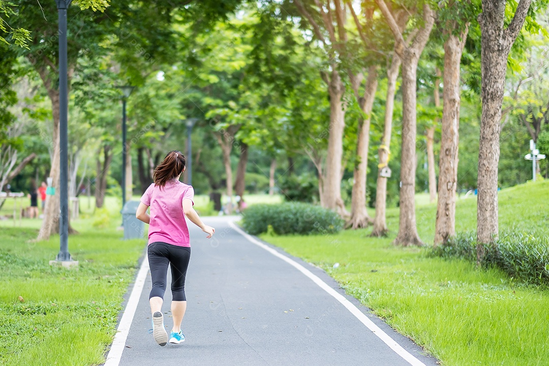 Mulher adulta jovem em roupas esportivas correndo no parque ao ar livre, mulher corredor correndo na estrada, atleta asiático andando e se exercitando de manhã. Conceitos de fitness, bem-estar, estilo de vida saudável e treino