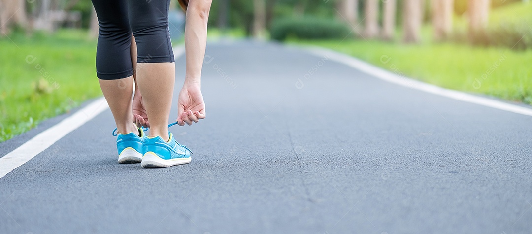 Mulher adulta jovem em roupas esportivas amarrando cadarço no parque outd