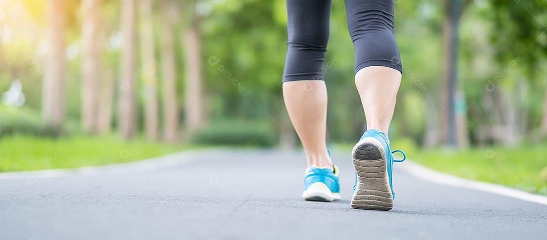 Mulher adulta jovem em sapatos esportivos correndo no parque ao ar livre.