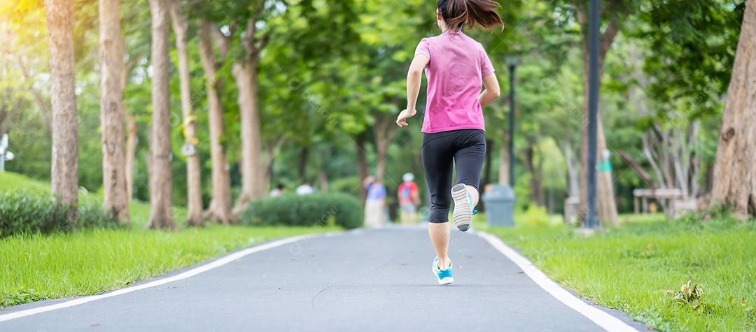 Mulher adulta jovem em roupas esportivas correndo no parque ao ar livre.