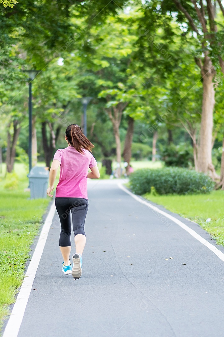 Mulher adulta jovem em roupas esportivas correndo no parque ao ar livre.