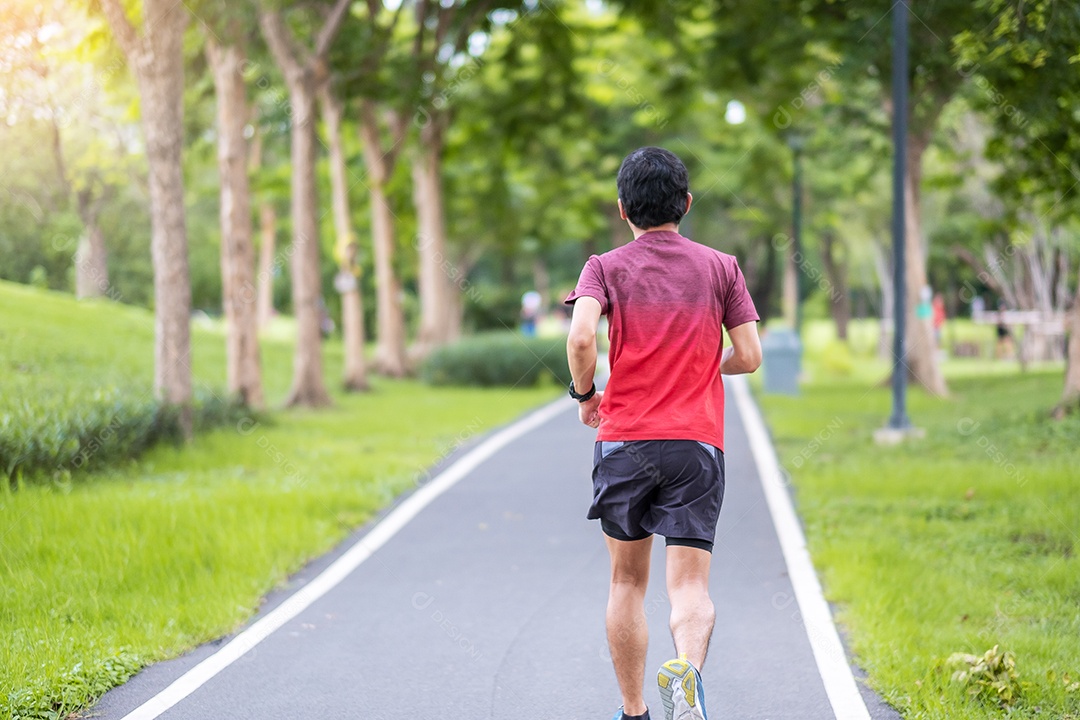 Macho adulto jovem em roupas esportivas correndo no parque ao ar livre, corrida.