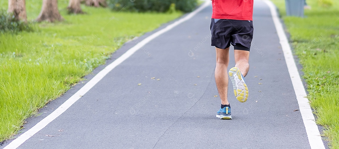 Macho adulto jovem em roupas esportivas correndo no parque ao ar livre, corrido