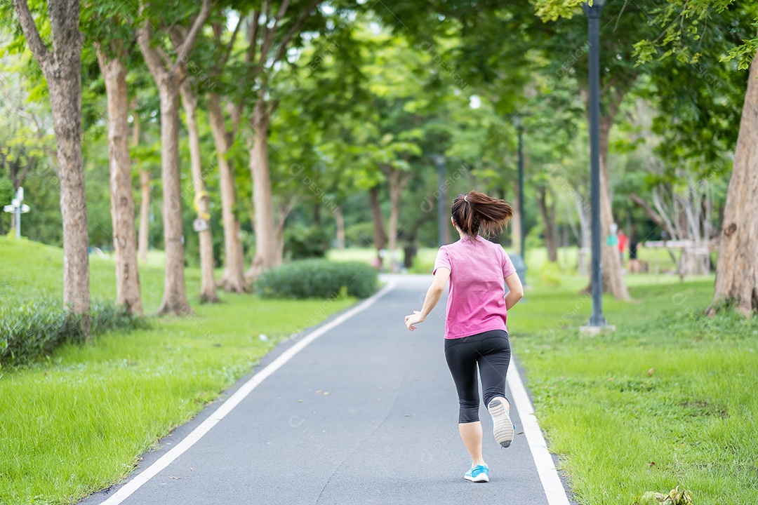 Mulher adulta jovem em roupas esportivas correndo no parque ao ar livre, mulher corredor correndo na estrada, atleta asiático andando e se exercitando de manhã. Conceitos de fitness, bem-estar, estilo de vida saudável e treino