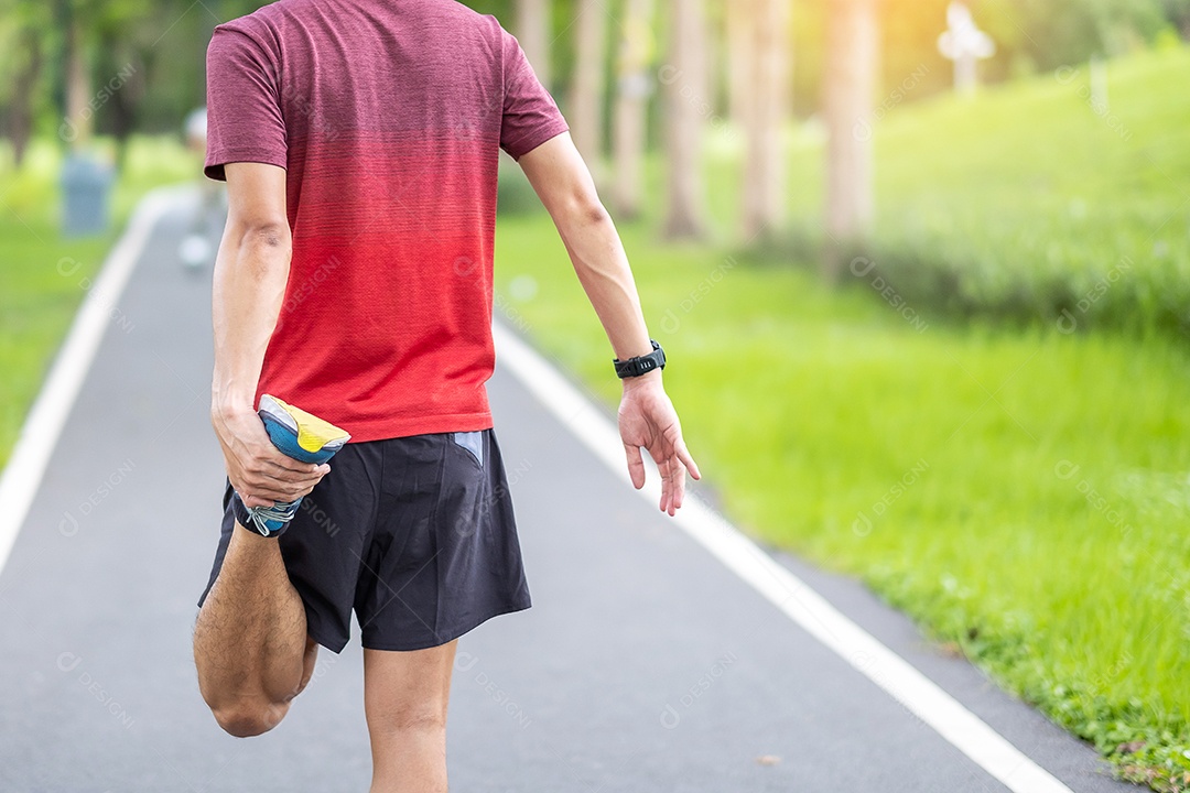 Homem adulto jovem em sportswear vermelho esticando o músculo no parque ao ar livre, homem corredor aquecer pronto para correr e correr de manhã. conceitos de bem-estar, fitness, exercício e estilo de vida saudável