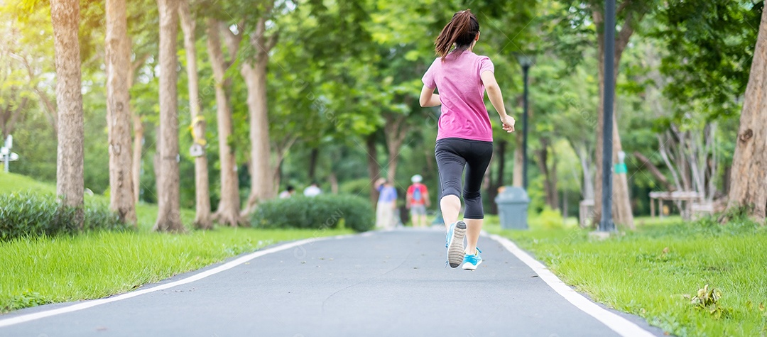 Mulher adulta jovem em roupas esportivas correndo no parque ao ar livre, mulher corredor correndo na estrada, atleta asiático andando e se exercitando de manhã. Conceitos de fitness, bem-estar, estilo de vida saudável e treino