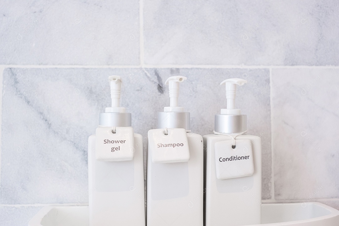 Garrafas de produtos de higiene pessoal no banheiro do hotel de luxo ou casa moderna. Conjunto de recipientes de chuveiro branco, gel de banho corporal, xampu e condicionador de cabelo em cerâmica com fundo de parede de mármore