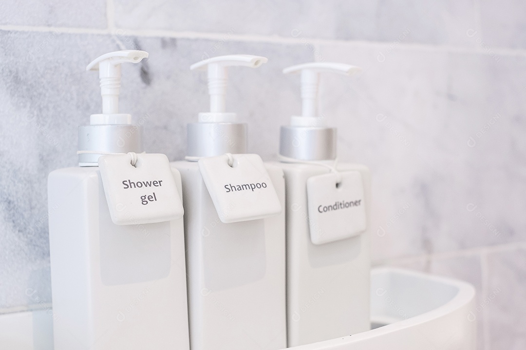 Garrafas de produtos de higiene pessoal no banheiro do hotel de luxo ou casa moderna. Conjunto de recipientes de chuveiro branco, gel de banho corporal, xampu e condicionador de cabelo em cerâmica com fundo de parede de mármore