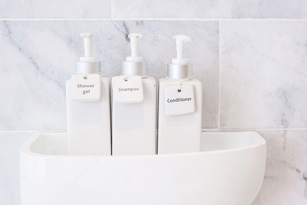 Garrafas de produtos de higiene pessoal no banheiro do hotel de luxo ou casa moderna. Conjunto de recipientes de chuveiro branco, gel de banho corporal, xampu e condicionador de cabelo em cerâmica com fundo de parede de mármore