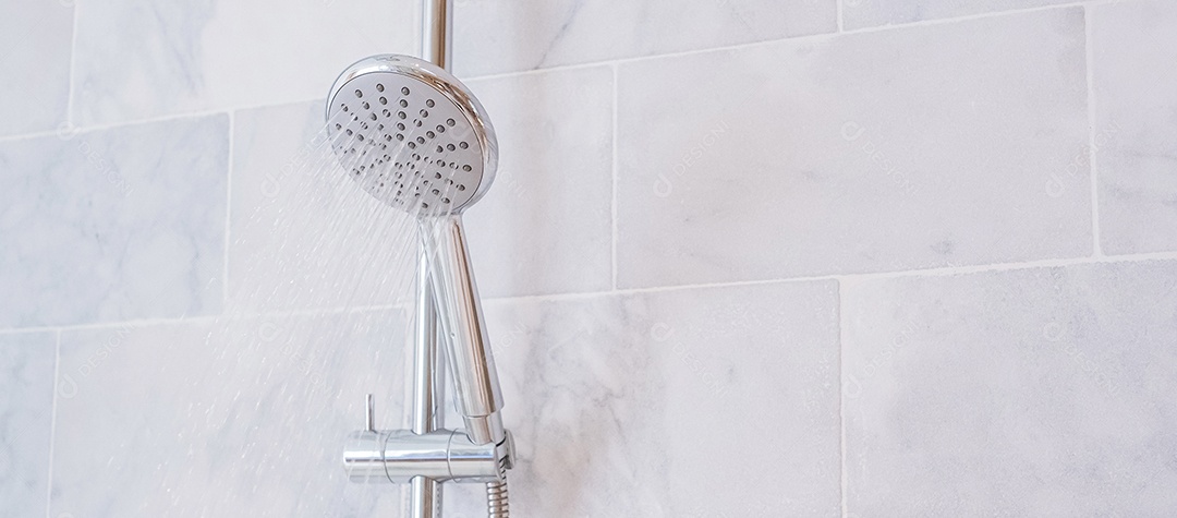 Gotas de água pulverizando ou correndo do chuveiro e torneira com fundo de parede de mármore no banheiro moderno