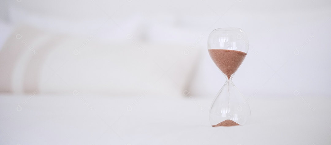 Ampulheta na cama à luz do sol da manhã, Areia fluindo através do bulbo da Ampulheta medindo o tempo de passagem. contagem regressiva, prazo, tempo de vida e aposentadoria, conceito de rotina diária