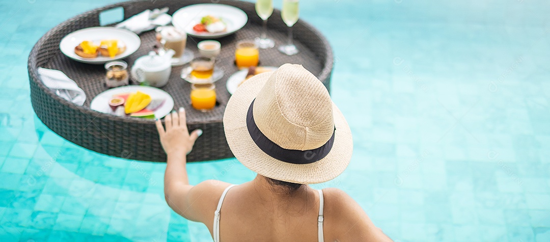 Mulher feliz em maiô branco com bandeja de café da manhã flutuante no hotel de piscina de luxo, jovem fêmea com chapéu desfrutar em resort tropical. Relaxante, viagens de verão exóticas, férias, férias e fim de semana