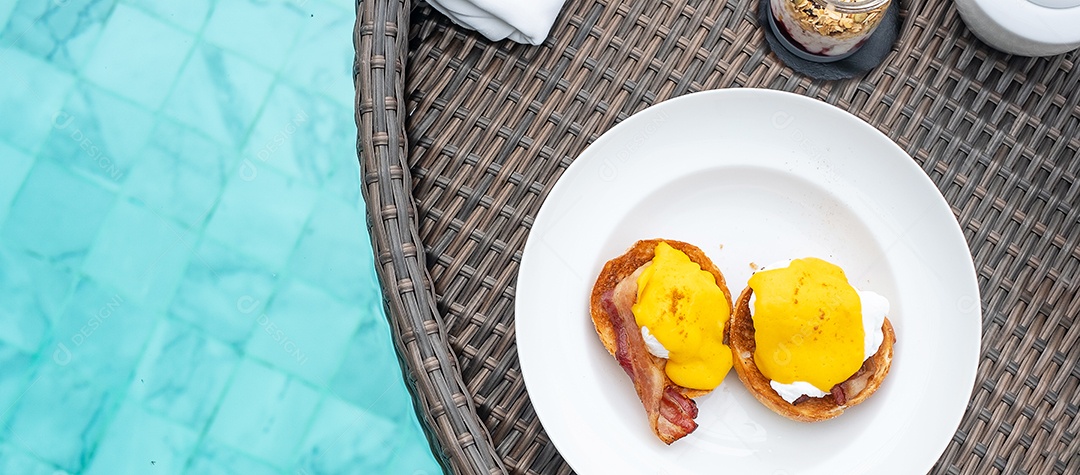 Bandeja flutuante de café da manhã na piscina no hotel de luxo ou villa de resort tropical; ovo escalfado com bacon defumado entremeado, muffin holandês e torrado e iogurte de cereais. viagens exóticas de verão