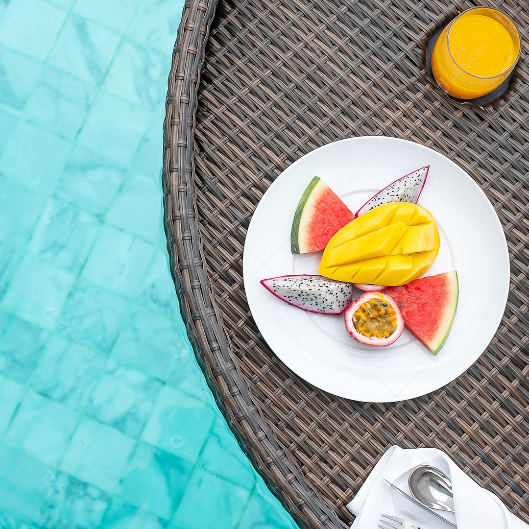 Bandeja flutuante de café da manhã na piscina no hotel de luxo ou villa de resort tropical, frutas; manga, pitaia melancia, maracujá e suco de laranja. Viagens de verão exóticas e conceito de comida saudável