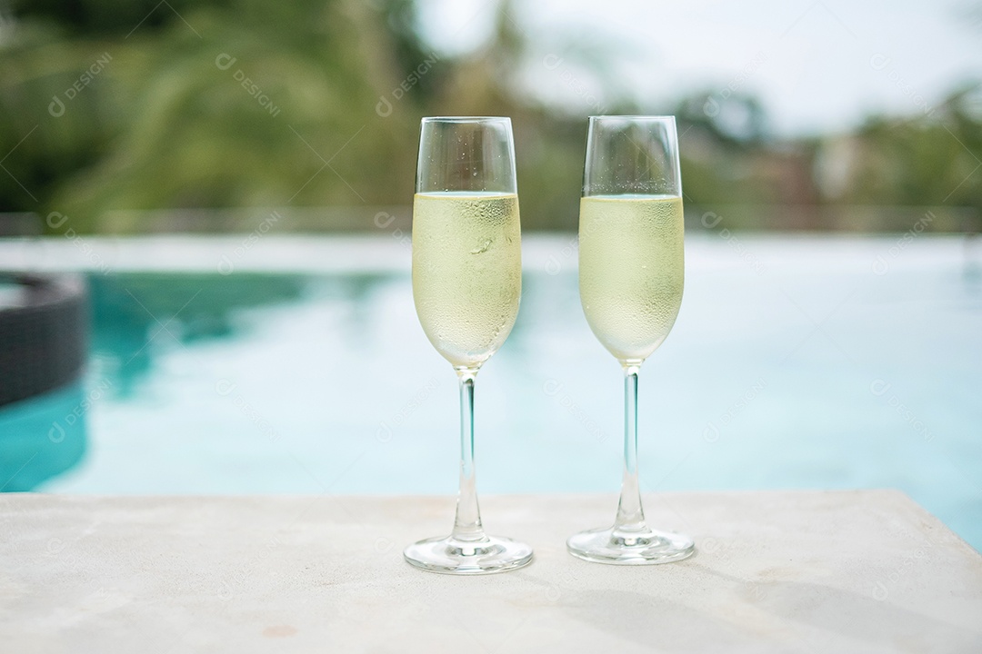 Duas taças de champanhe espumantes ou prosecco perto da piscina.
