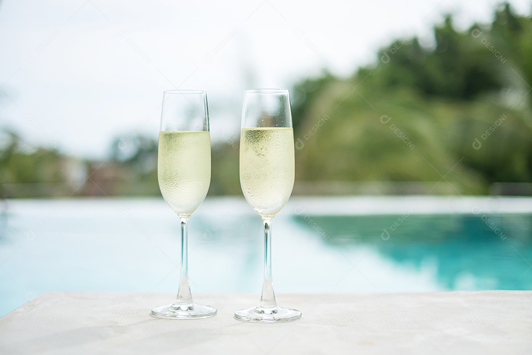 Duas taças de champanhe espumantes ou prosecco perto da piscina.