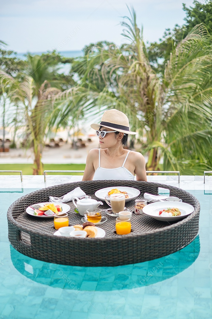 Mulher feliz em maiô branco com bandeja flutuante de café da manhã no hotel de piscina de luxo, jovem mulher com óculos de sol desfruta em resort tropical. Relaxante, viagens de verão exóticas, férias, férias e fim de semana