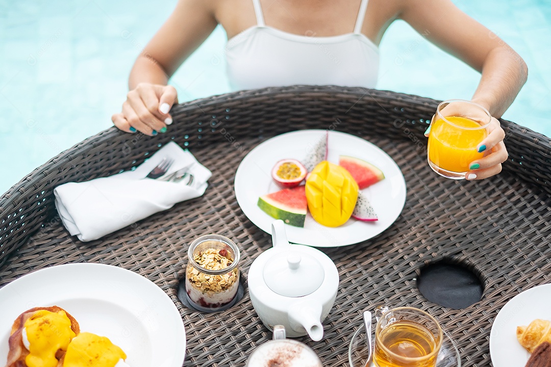 Mulher feliz em maiô branco com bandeja flutuante de café da manhã no hotel de piscina de luxo, jovem fêmea com prazer em resort tropical. Relaxante, viagens de verão exóticas, férias, férias e fim de semana