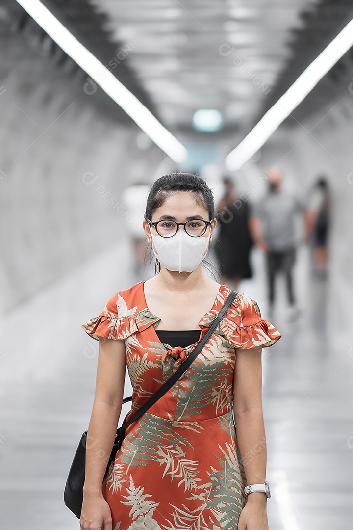 Jovem garota asiática usando máscara facial cirúrgica protege a inflexão de coronavírus, turista feliz andando na estação de metrô pública. distanciamento social, novo normal e vida após a pandemia de covid-19