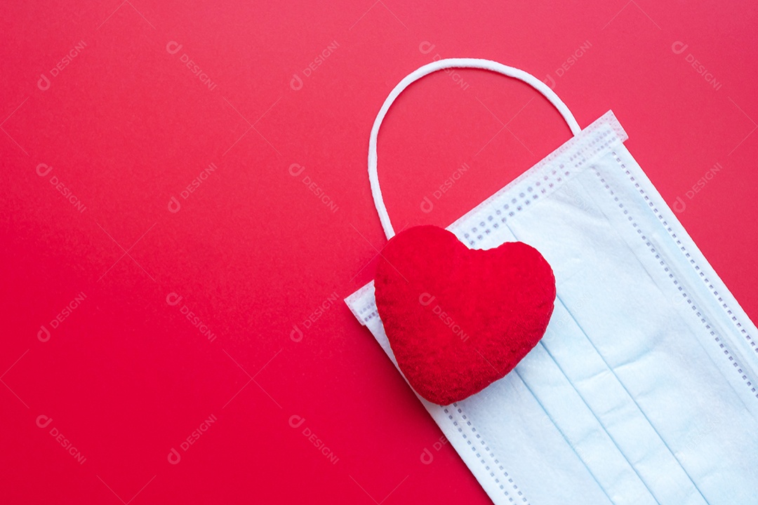 Decoração em forma de coração e máscara facial médica em fundo vermelho contra infecção por doença de coronavírus. Amor, juntos e feliz dia dos namorados sob o conceito de pandemia Covid-19
