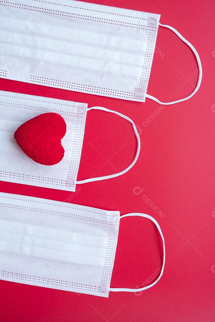 Decoração em forma de coração e máscara facial médica em fundo vermelho contra infecção por doença de coronavírus. Amor, juntos e feliz dia dos namorados sob o conceito de pandemia Covid-19