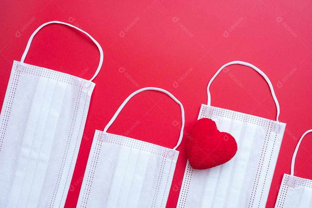 Decoração em forma de coração e máscara facial médica em fundo vermelho contra infecção por doença de coronavírus. Amor, juntos e feliz dia dos namorados sob o conceito de pandemia Covid-19