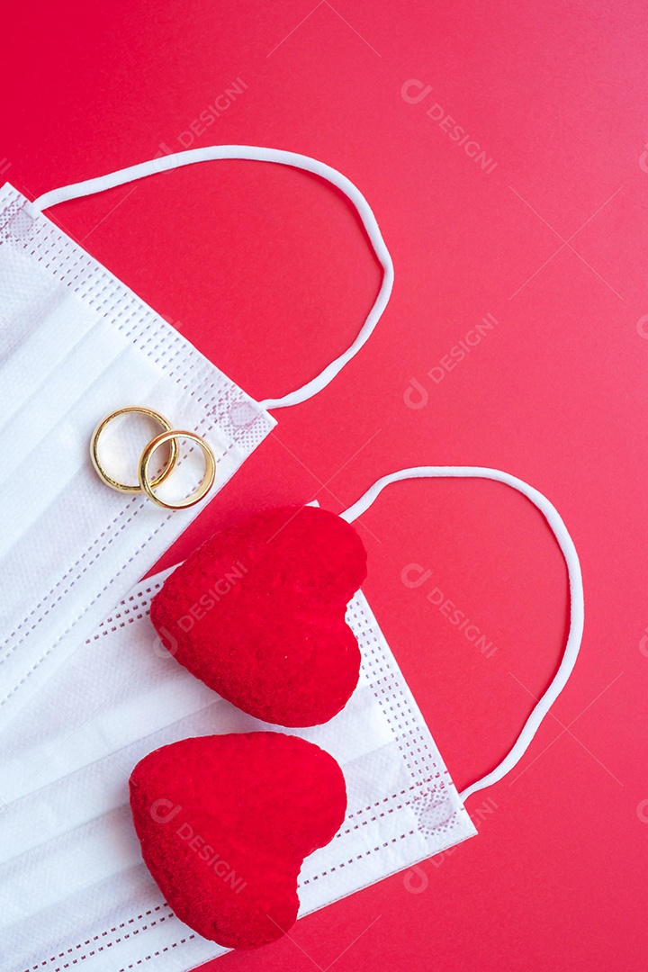 Decoração em forma de coração, anel de noivado dourado e máscara facial médica em fundo vermelho contra infecção por doença de coronavírus. Amor, juntos e feliz dia dos namorados sob o conceito de pandemia Covid-19