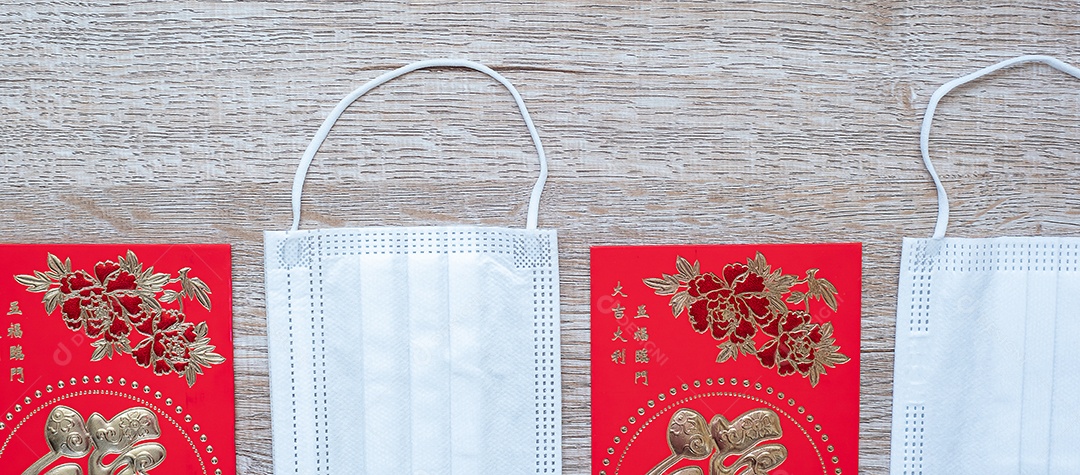 Red envelope or Ang pao and medical face mask against Coronavirus disease infection. The Chinese character means happiness or good luck, and the Chinese phrase means luck and wealth. Lunar New Year