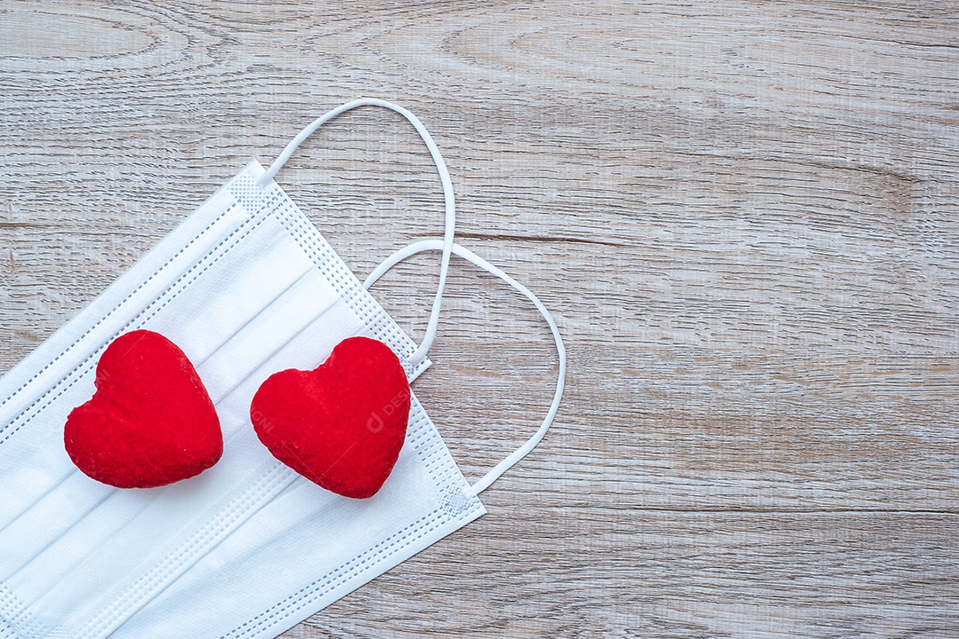 Decoração em forma de coração e máscara facial médica no fundo da mesa contra a infecção por doença de coronavírus. Amor, juntos e feliz dia dos namorados sob o conceito de pandemia Covid-19