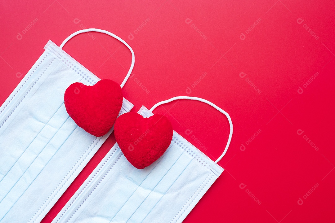 Decoração em forma de coração e máscara facial médica em fundo vermelho contra infecção por doença de coronavírus. Amor, juntos e feliz dia dos namorados sob o conceito de pandemia Covid-19