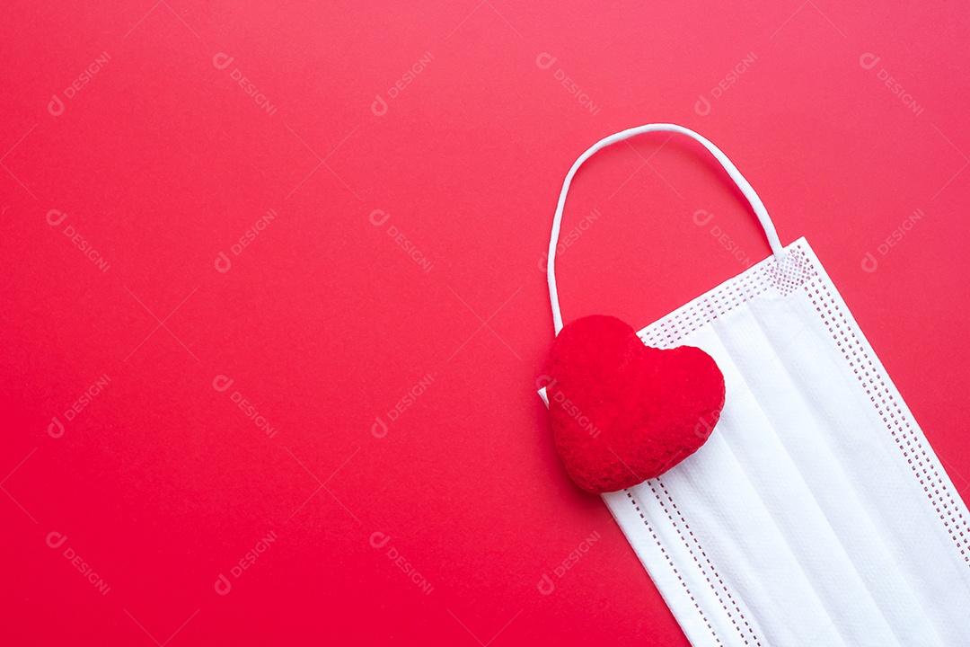 Decoração em forma de coração e máscara facial médica em fundo vermelho contra infecção por doença de coronavírus. Amor, juntos e feliz dia dos namorados sob o conceito de pandemia Covid-19