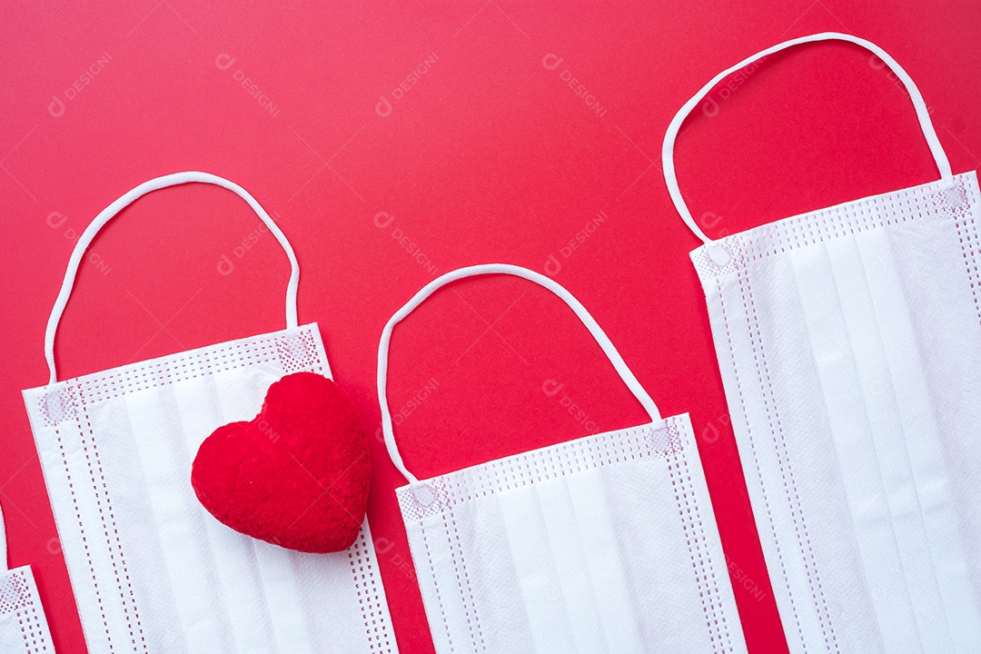 Decoração em forma de coração e máscara facial médica em fundo vermelho contra infecção por doença de coronavírus. Amor, juntos e feliz dia dos namorados sob o conceito de pandemia Covid-19