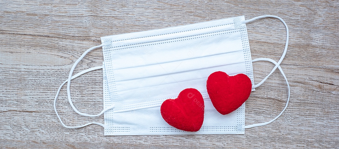 Decoração em forma de coração e máscara facial médica no fundo da mesa contra a infecção por doença de coronavírus. Amor, juntos e feliz dia dos namorados sob o conceito de pandemia Covid-19
