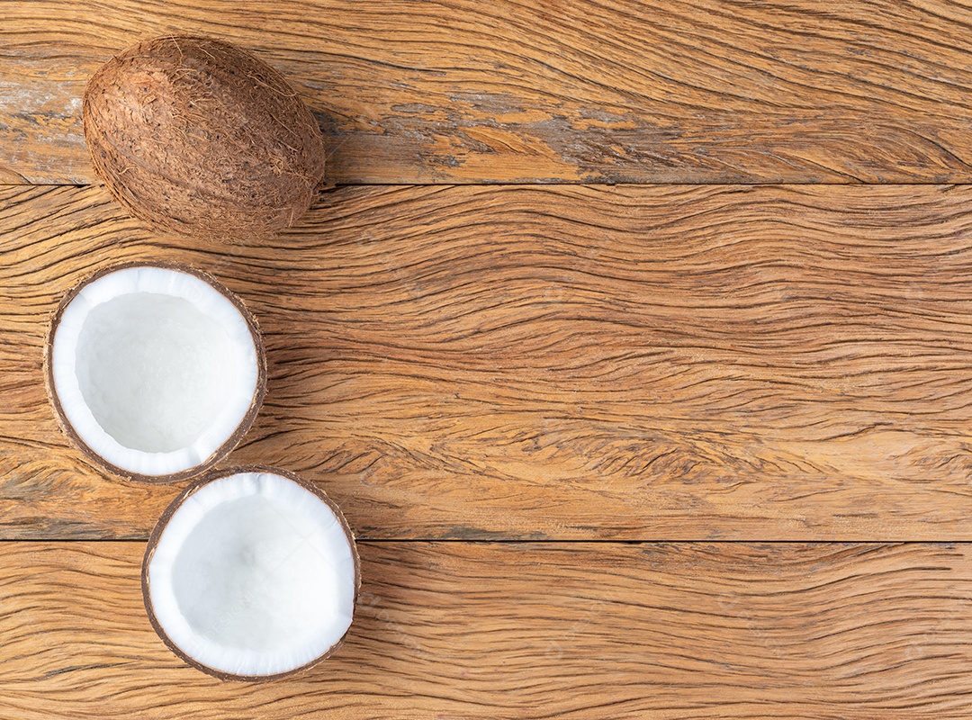 Coco e meia fruta rachada sobre a mesa de madeira
