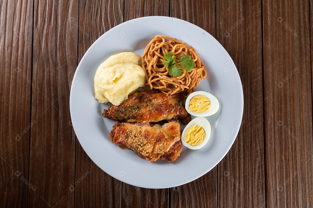 Prato de comida de almoço. Macarrão com frango assado, purê e ovos. fundo de madeira.