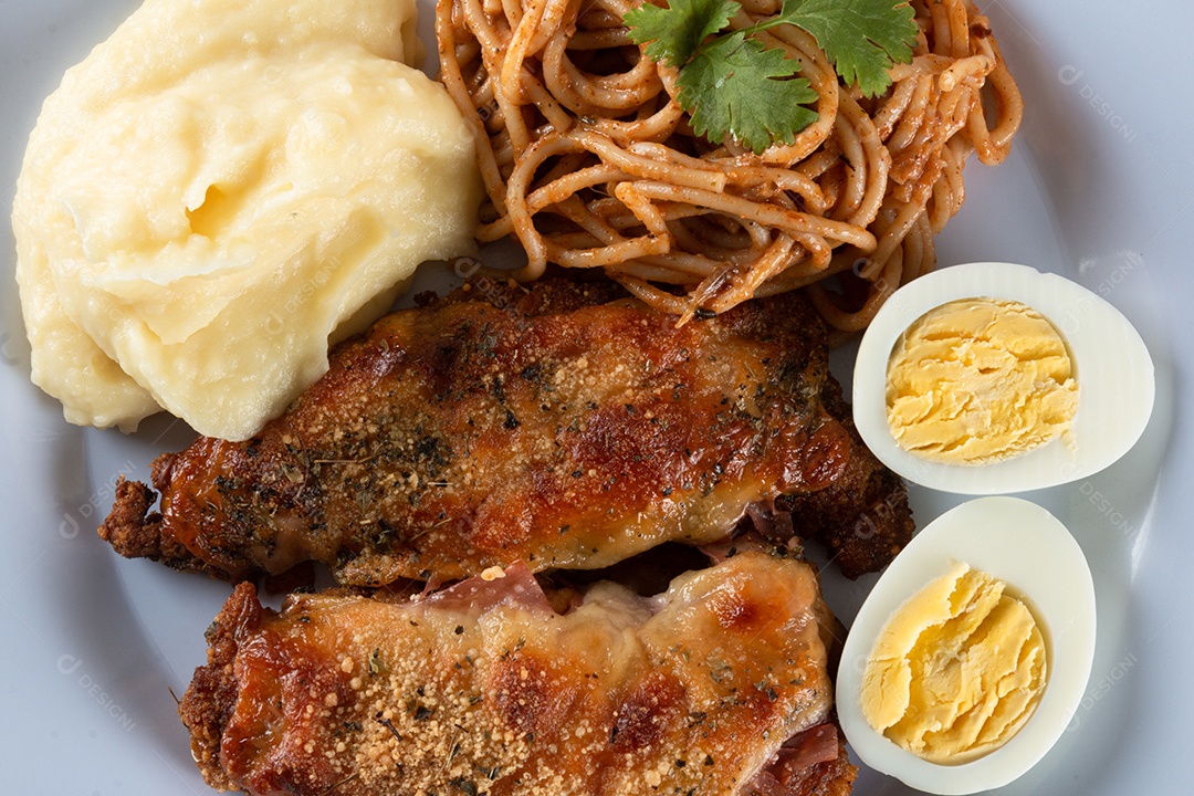 Prato de comida de almoço. Macarrão com frango assado, purê e ovos. fundo de madeira.