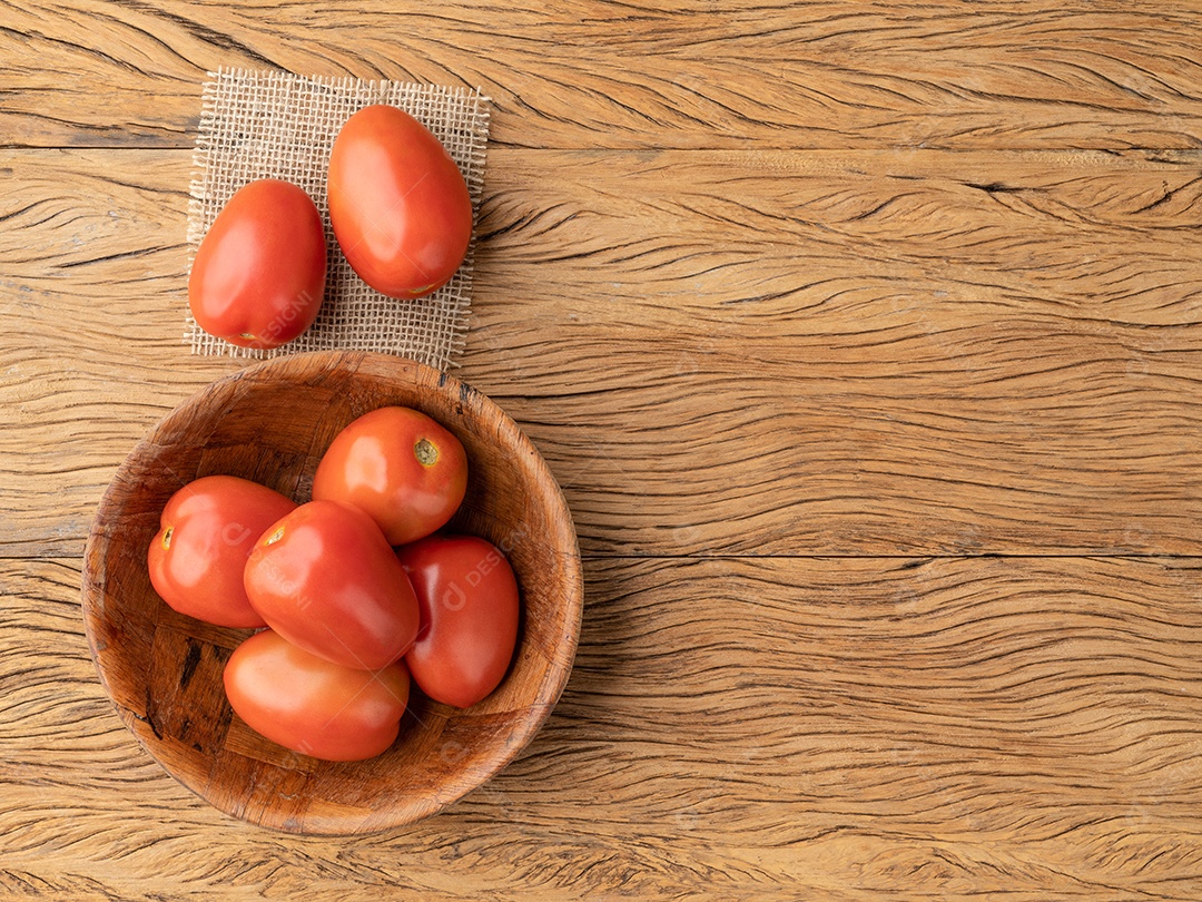 Tomates vermelhos em uma tigela sobre a mesa de madeira