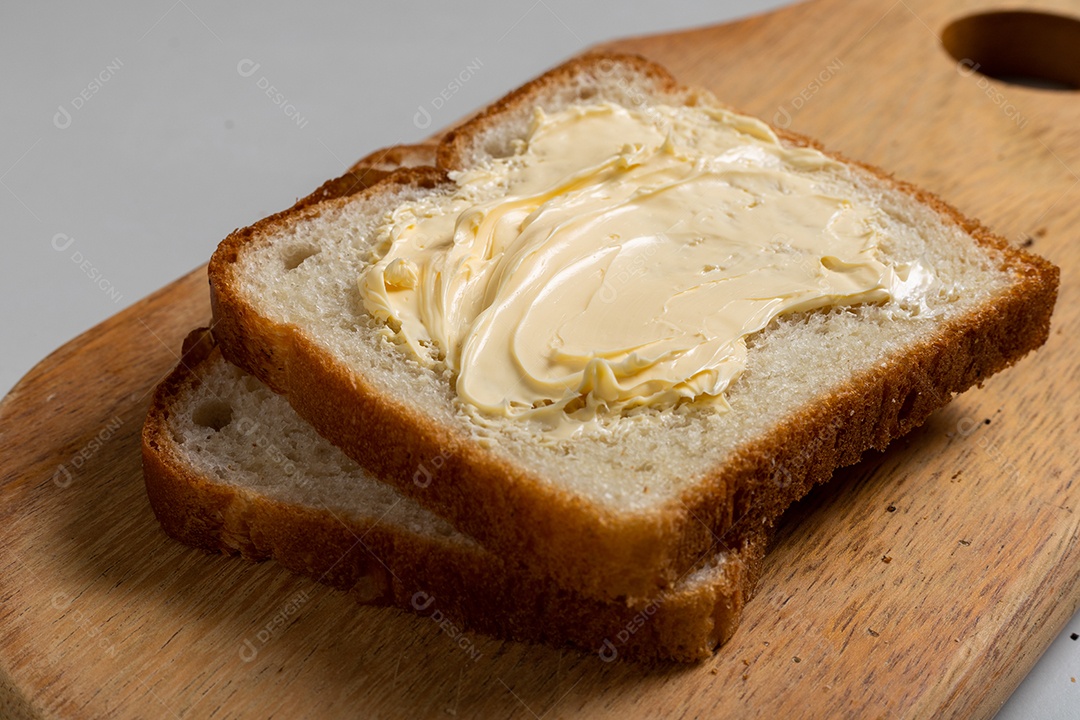 Pão de pão torrado com margarina em uma madeira sobre a mesa.