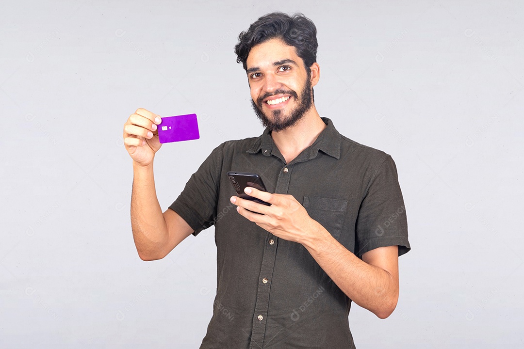 Homem jovem barbudo usando seu celular para fazer compras cartão de crédito sobre fundo isolado branco